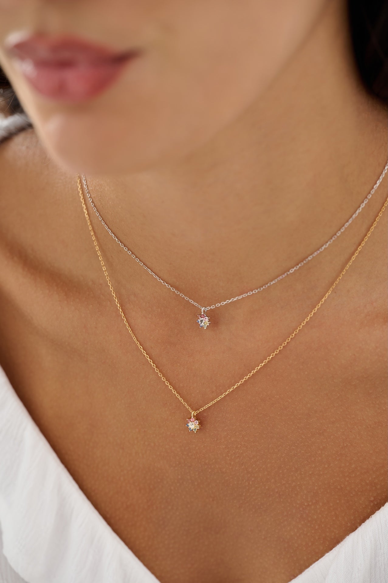 Close-up of a person wearing two delicate necklaces with small pendants.