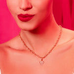 Woman wearing a gold necklace against a pink background