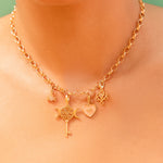 Gold necklace with charms on a person against a green background