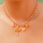 Gold necklace with charms on a person against a green background