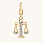 Gold pendant with a design resembling the scales of justice on a white background
