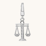 Silver pendant with a design resembling the scales of justice on a white background