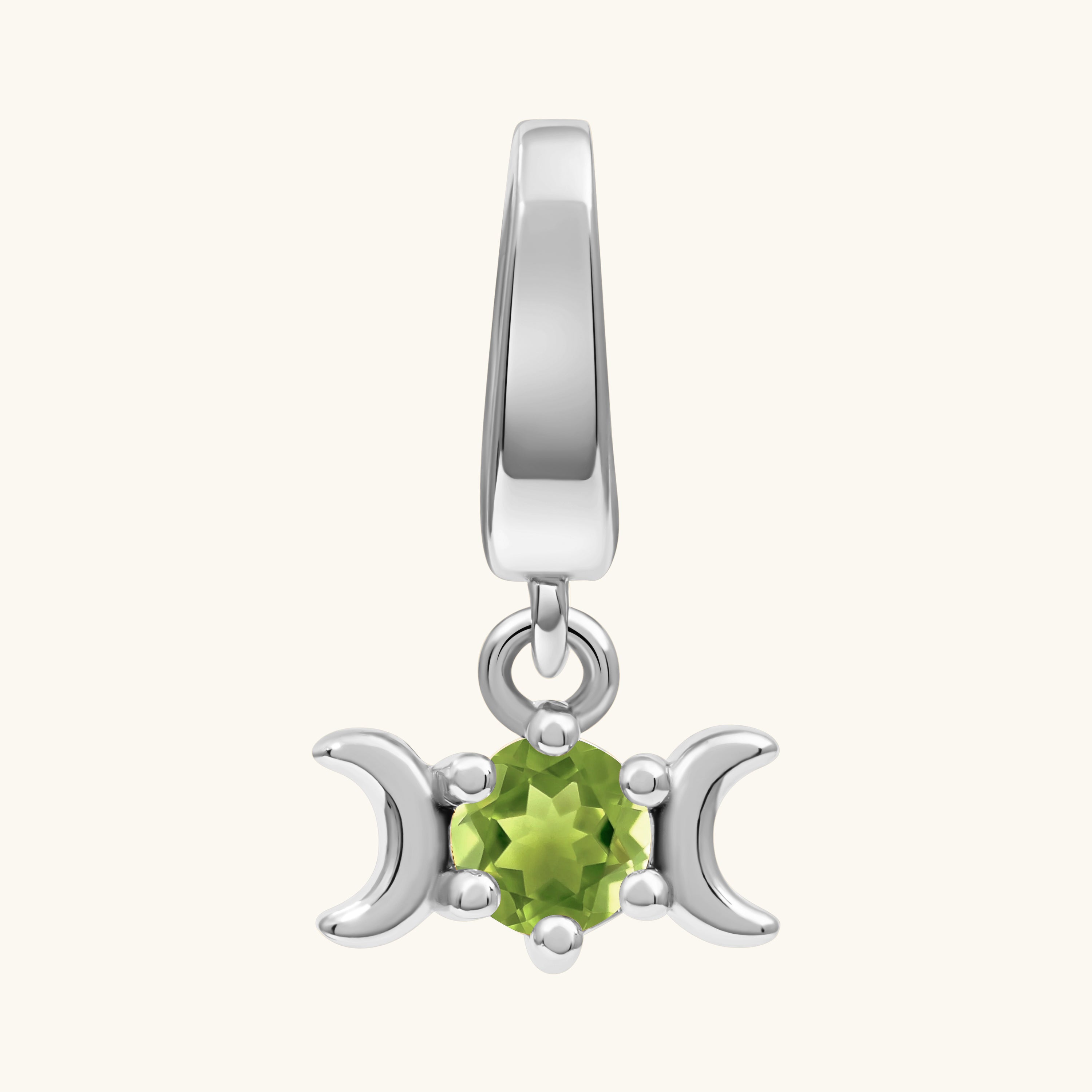 A sterling silver triple moon charm featuring a central faceted green peridot gemstone, set against a plain off-white background.