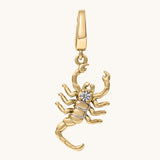Gold scorpion-shaped pendant with a white topaz stone on a white background