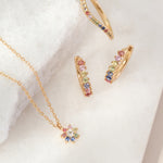 Gold jewelry set with colorful gemstones on a white background