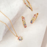 Gold jewelry set with colorful gemstones on a white background
