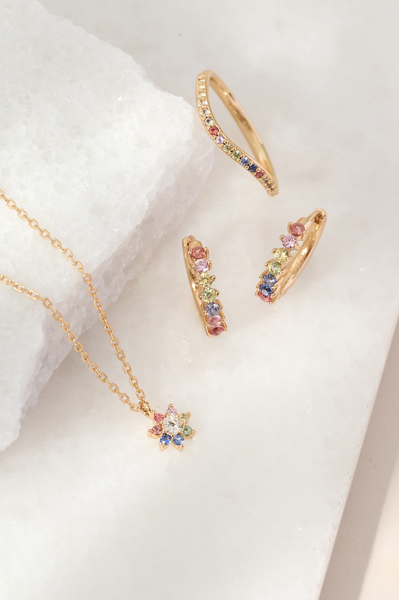 Gold jewelry set with colorful gemstones on a white background