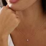 Close-up of a person wearing a delicate necklace with a small pendant.