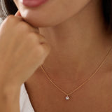 Close-up of a person wearing a delicate necklace with a small pendant.