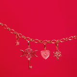 Rose gold bracelet with charms on a red background