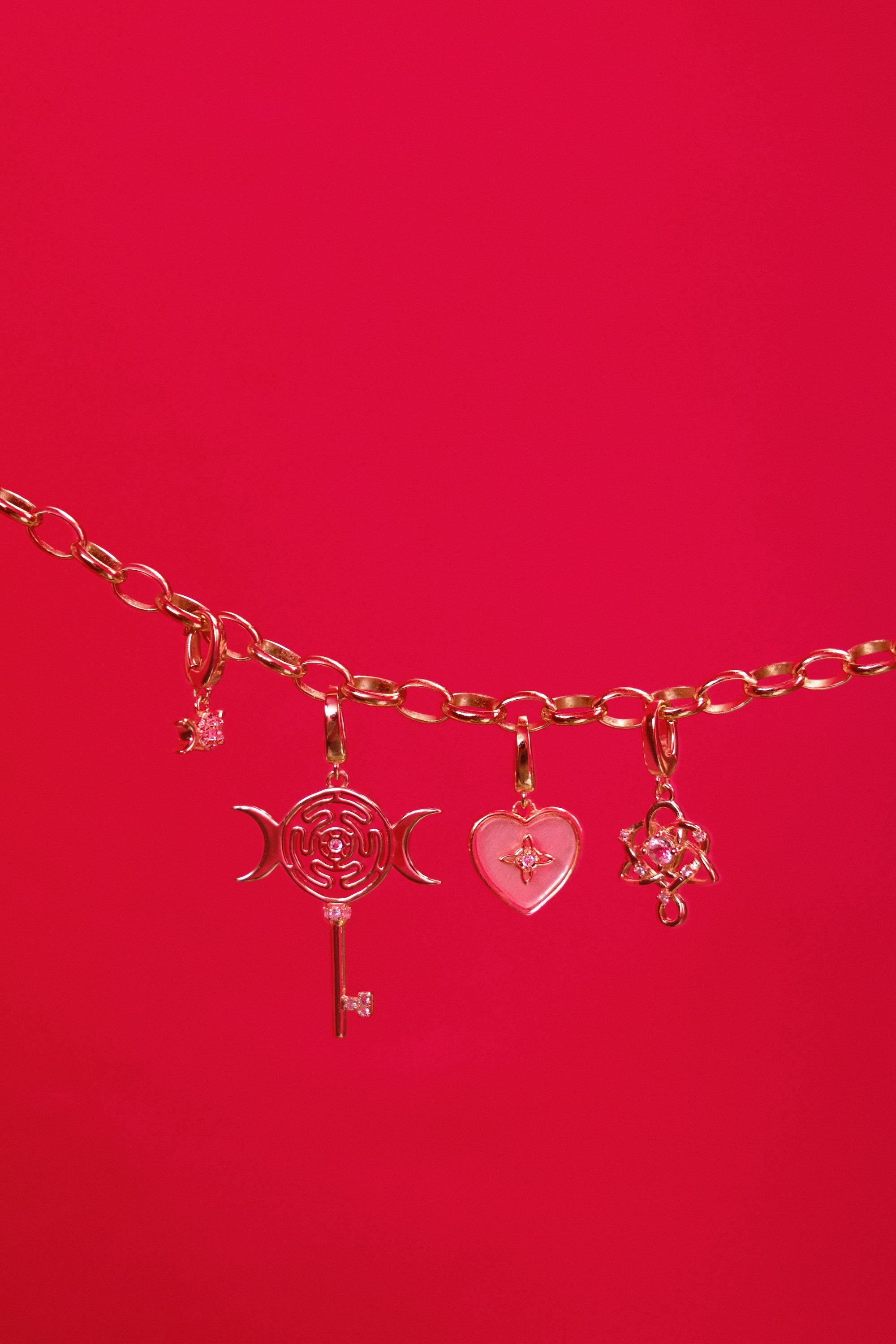 Rose gold bracelet with charms on a red background