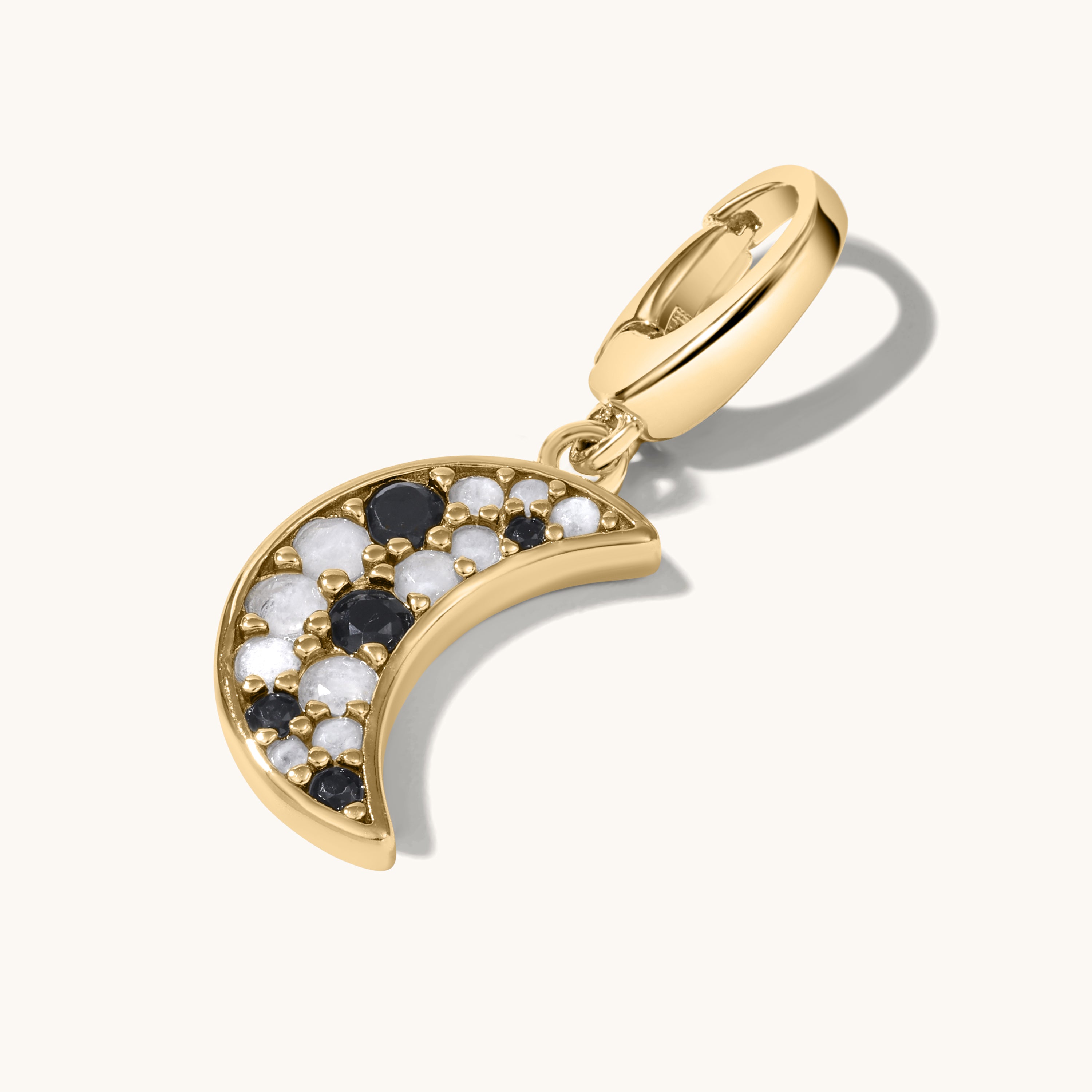 Gold crescent moon charm with clustered black and white gemstones