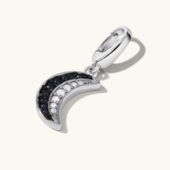 Silver crescent moon charm with black and white gemstone inlay.