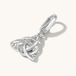 Stone studded Silver Triquetra symbol charm lying on a light cream background with shadow
