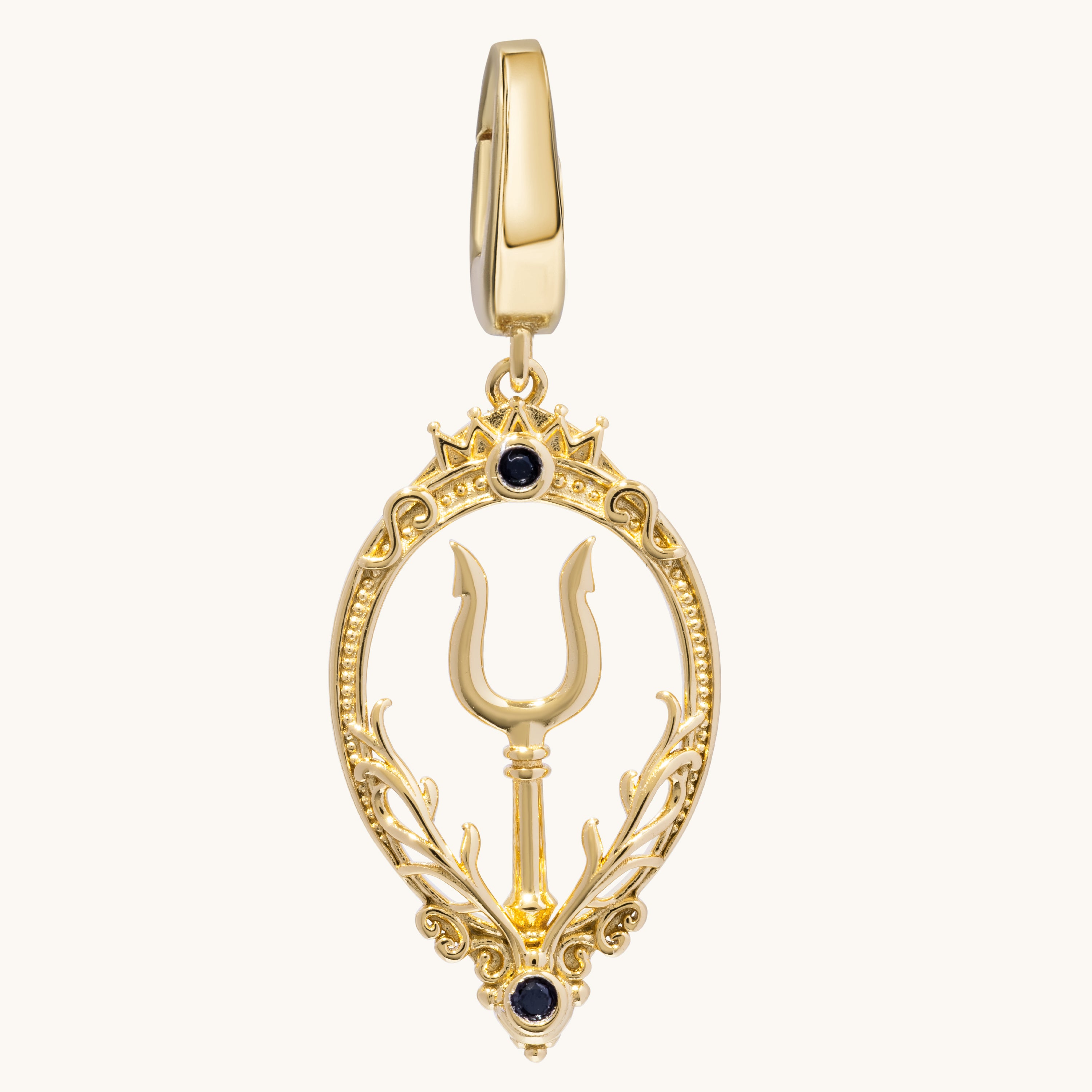 A gold-plated pendant featuring a central trident symbol enclosed in an ornate oval frame with decorative leaf-like flourishes and two small black gemstone accents, shown on a plain off-white background.