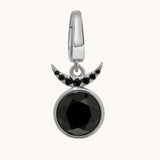 A silver crescent moon and full moon pendant charm featuring a large faceted black gemstone and small black accent stones, shown on a light cream background.