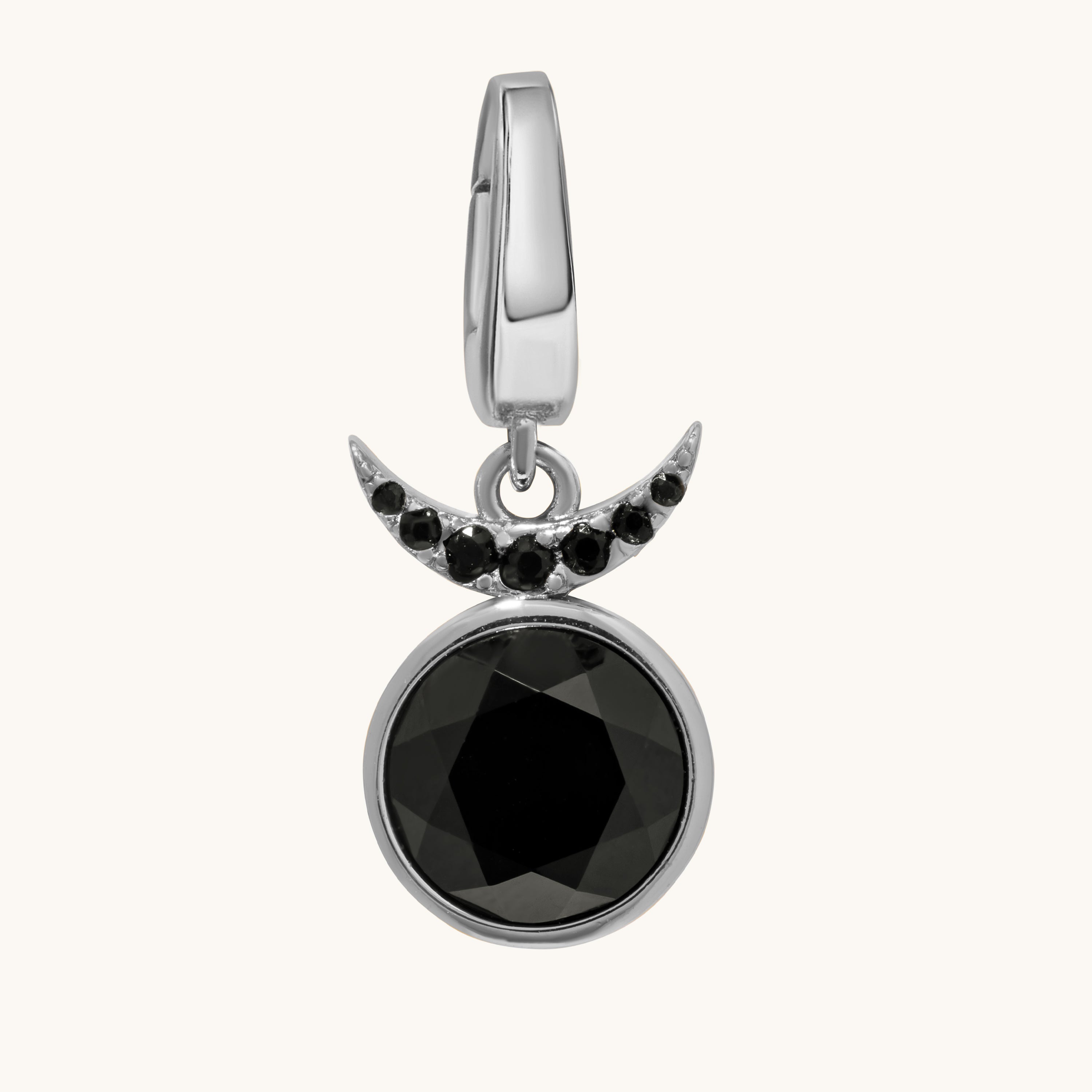 A silver crescent moon and full moon pendant charm featuring a large faceted black gemstone and small black accent stones, shown on a light cream background.
