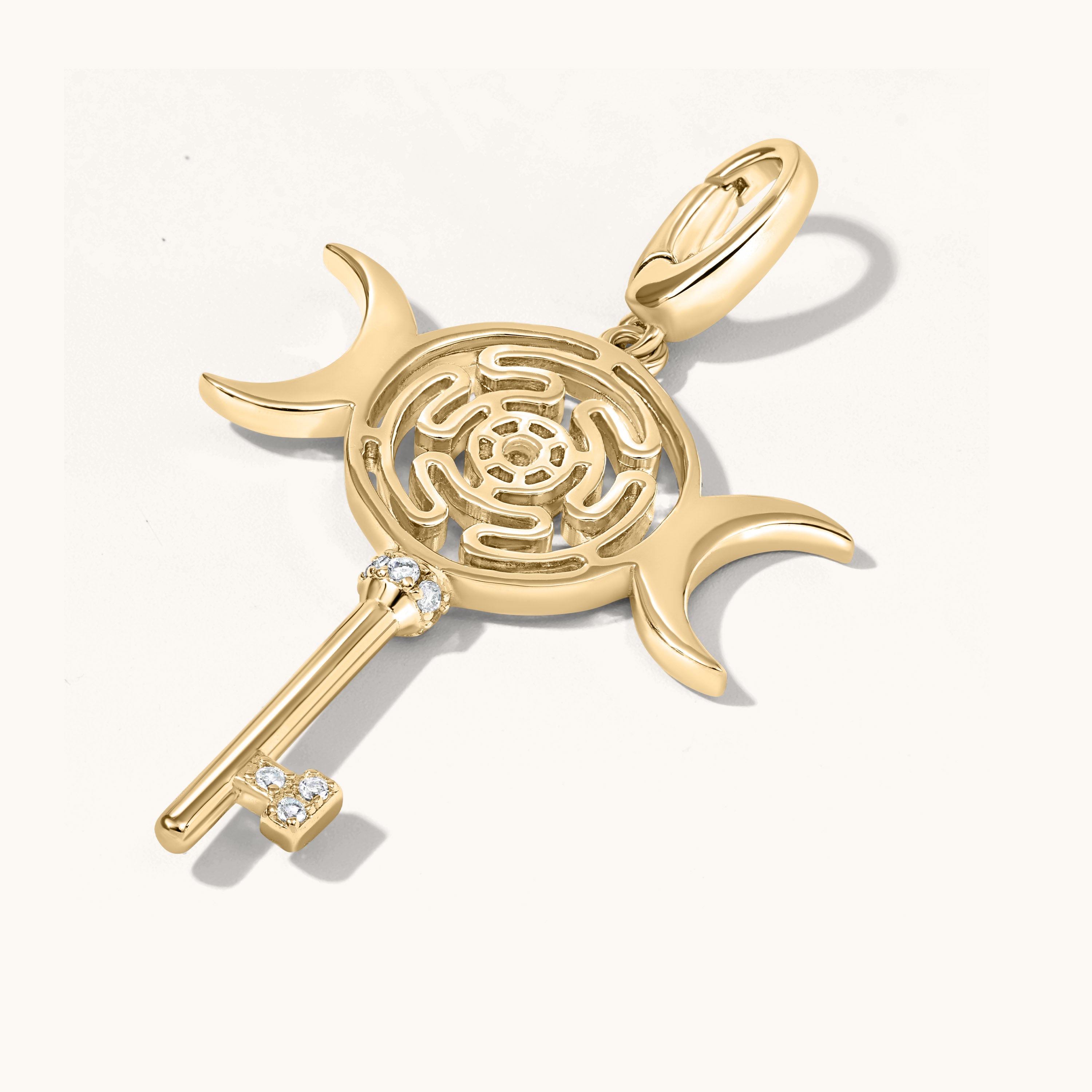 Gold pendant with maze design and key on a white background