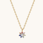 Gold necklace with a colorful flower-shaped pendant on a white background