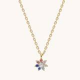 Gold necklace with a colorful flower-shaped pendant on a white background