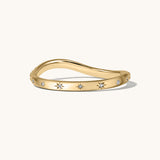 Gold ring with small white starburst stones on a white background