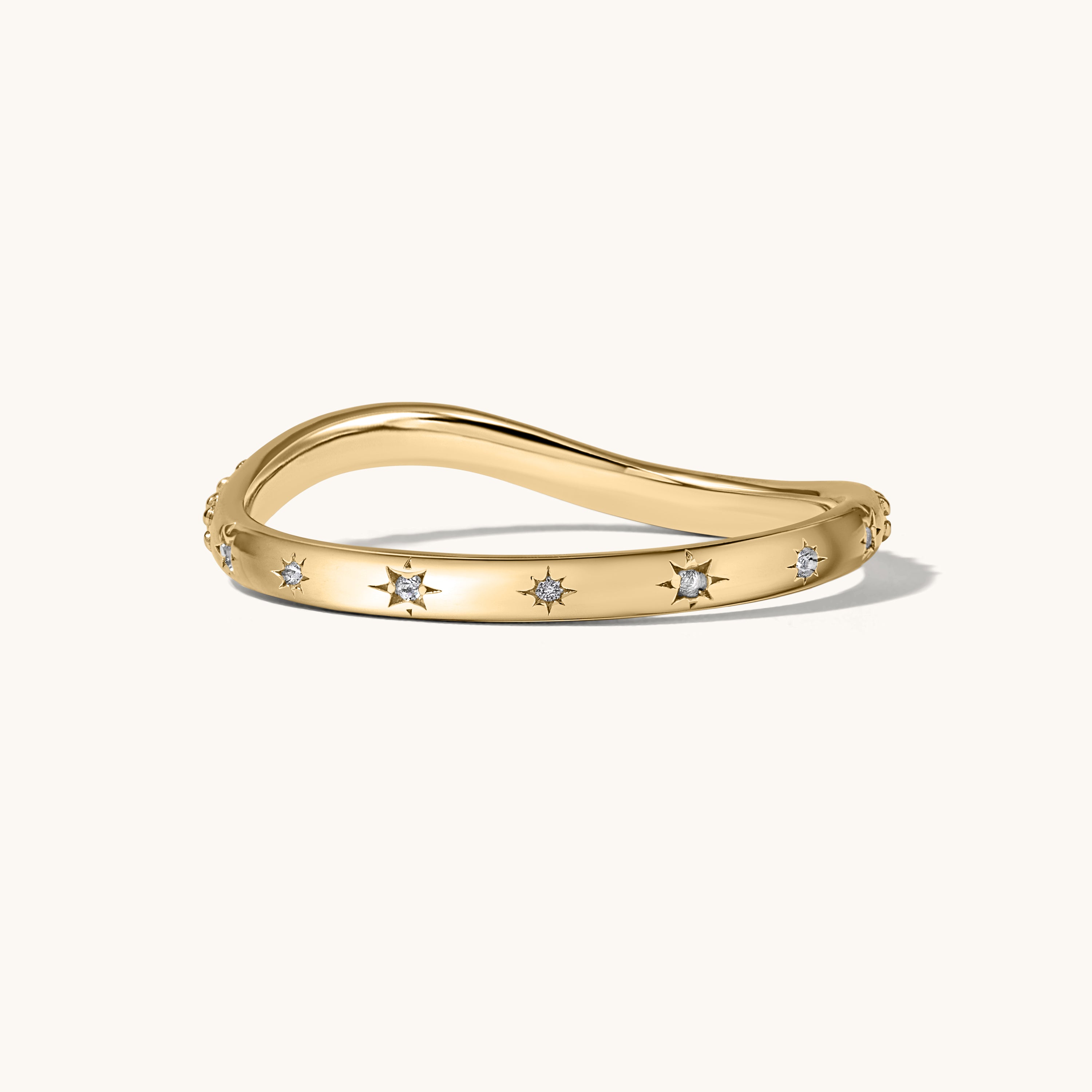 Gold ring with small white starburst stones on a white background