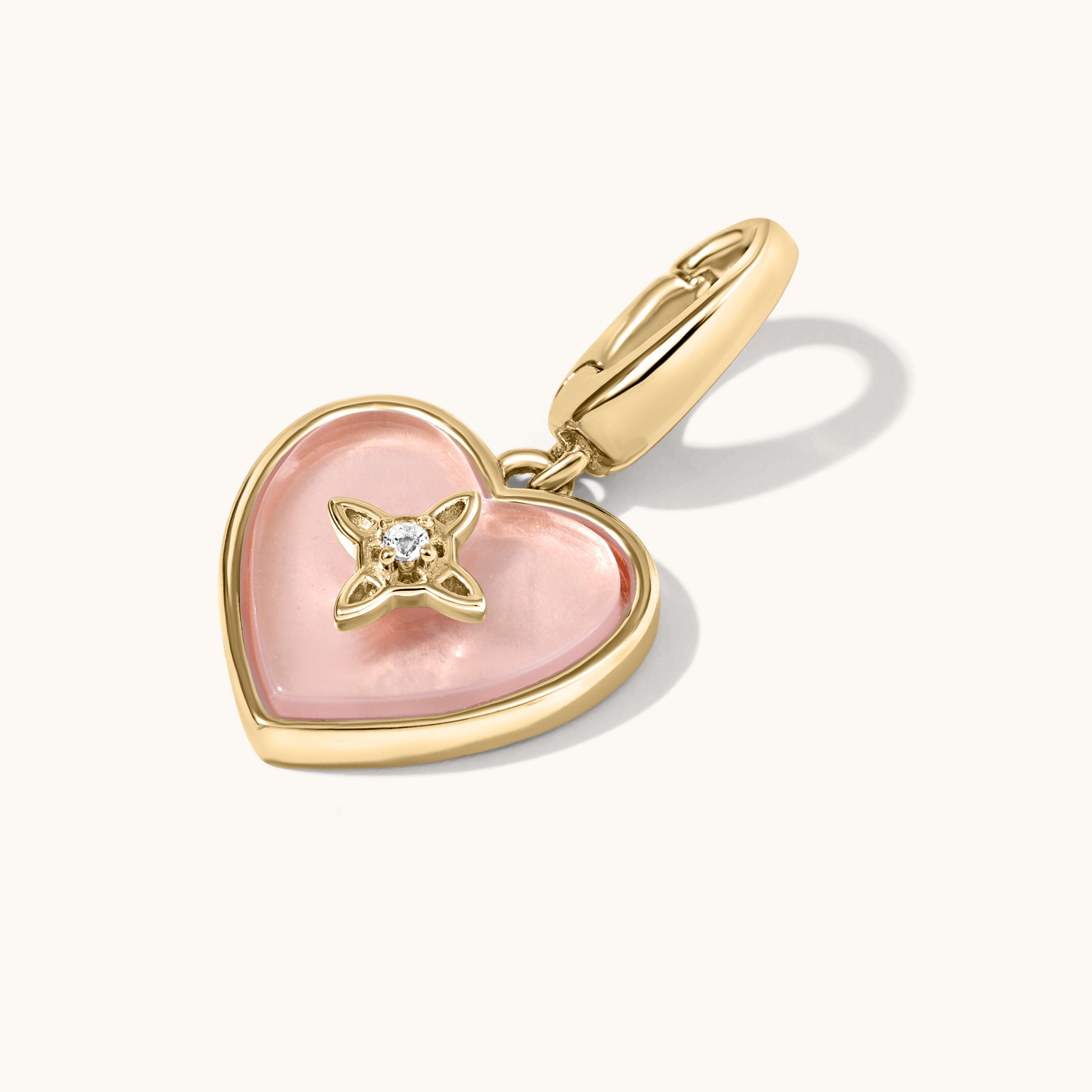 Heart-shaped pendant with pink rose quartz and gold accents on a white background