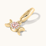 Gold charm with a pink gemstone on a white background