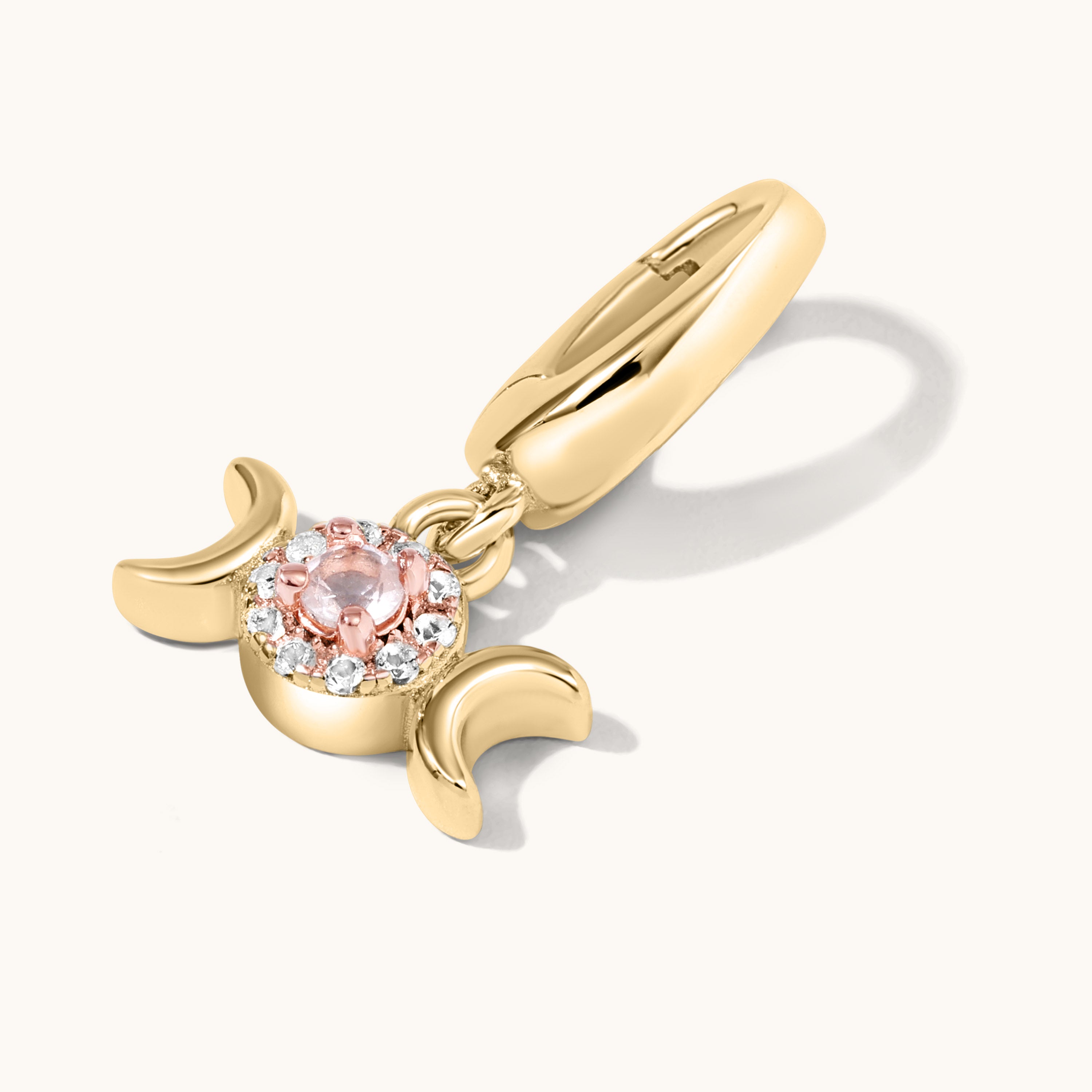 Gold charm with a pink gemstone on a white background