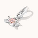 Silver charm with a pink gemstone on a white background