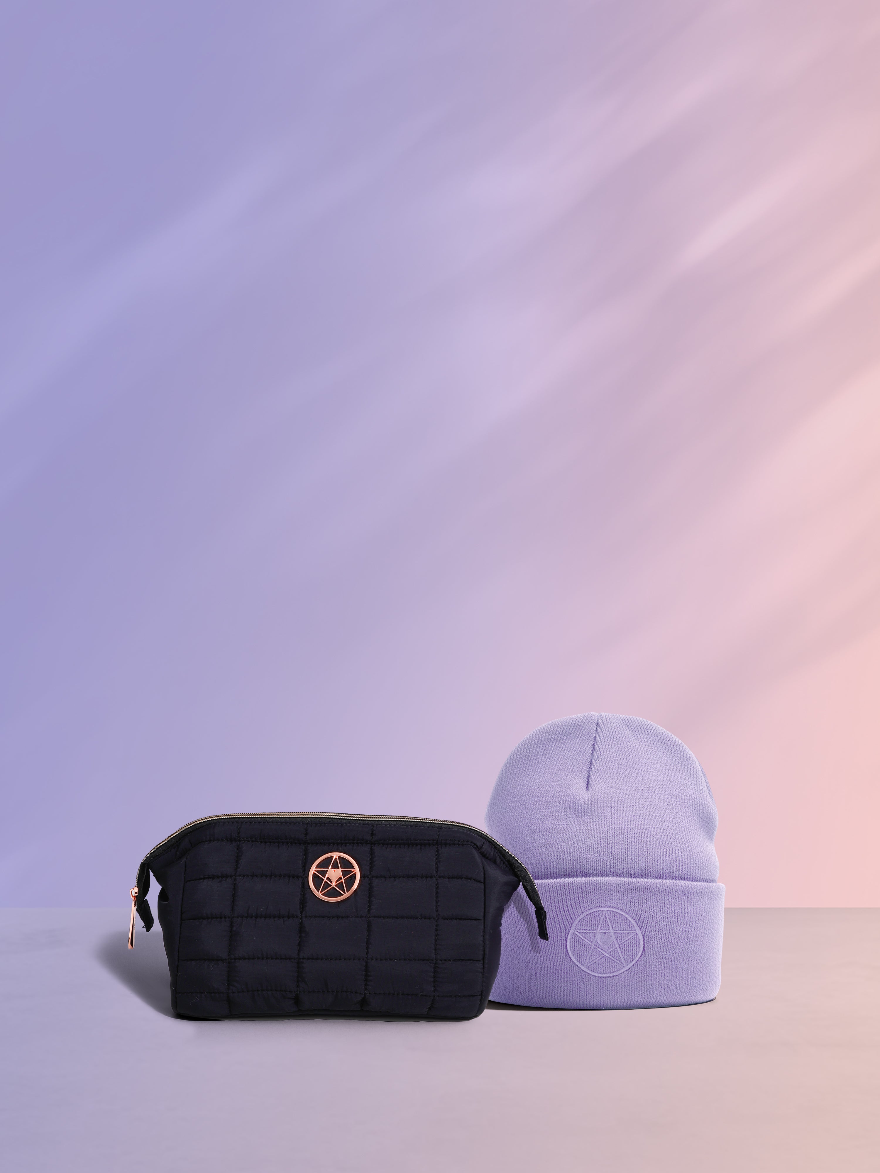 Black quilted pouch with gold emblem and light purple beanie on a gradient background