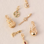 7 Goddess charms in Gold lying on an elegant cream base flatlay style, including Goddess Bastet, Brigid, Selene, Circe, Cerridwen, Artemis and Hestia.