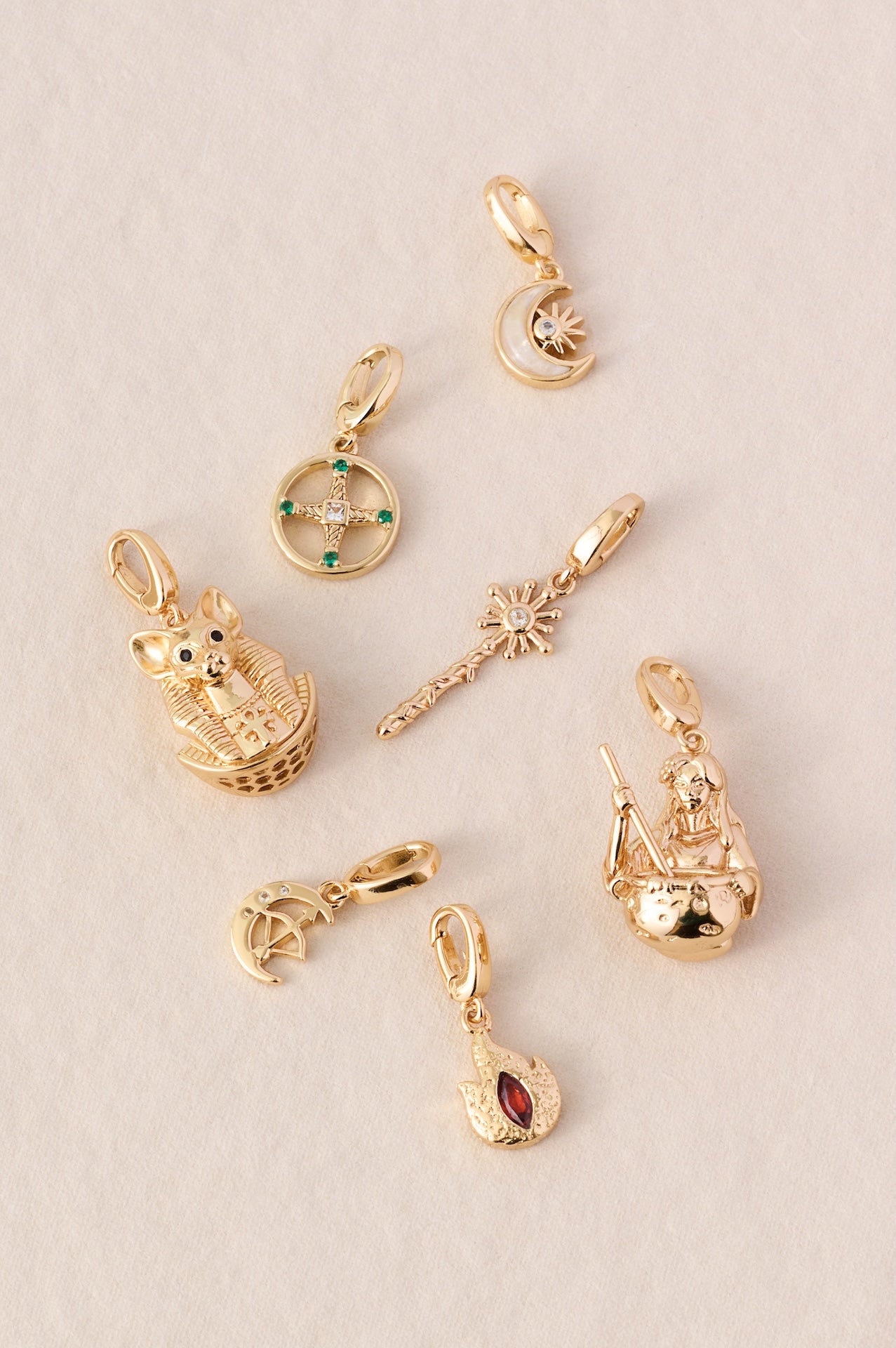 7 Goddess charms in Gold lying on an elegant cream base flatlay style, including Goddess Bastet, Brigid, Selene, Circe, Cerridwen, Artemis and Hestia.