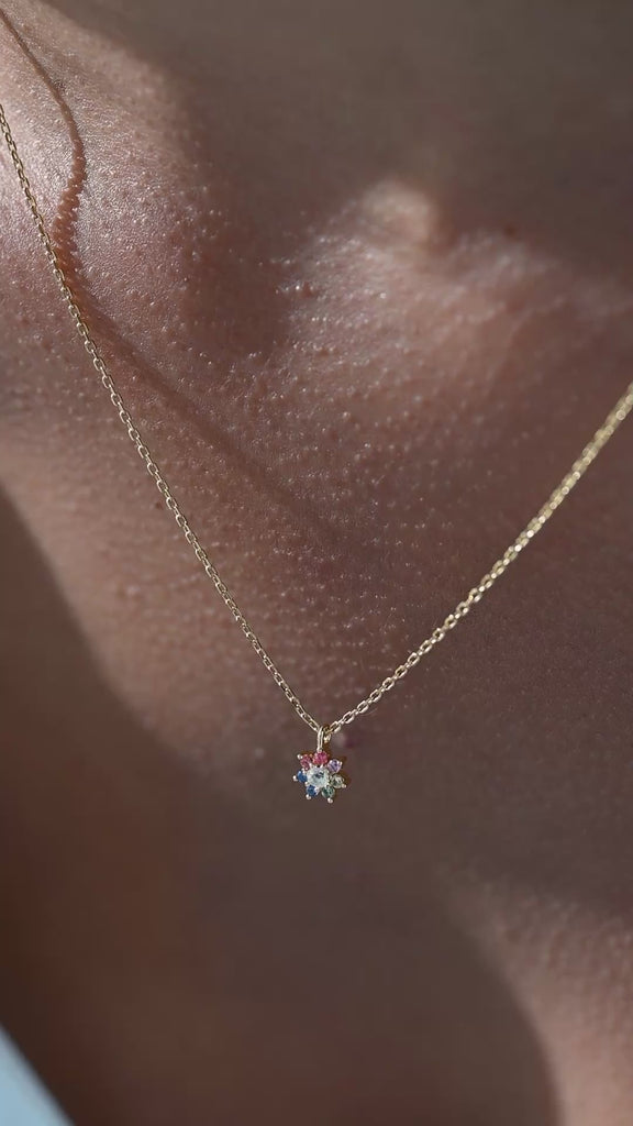 Woman wearing flower pendant necklace and touching it.