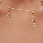 Close-up video of a model sliding gold triquetra and ‘magickal’ charms along a necklace chain, then zooming out to show her wearing the necklace on a beach.